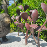 一株株銅葉舒展枝姿，在陽光下閃耀生命的光澤，鳥兒靜靜守望，為街道增添自然的詩意。