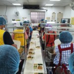 新業(yè)同仁與志工們繫上圍裙、套上防塵帽，戴上口罩，手捧一份份飯包各司其職，為的是準(zhǔn)時(shí)將熱騰騰的飯包送到長(zhǎng)輩手中。