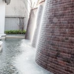 與接待大廳相對(duì)，僅隔一道玻璃落地窗即為「戶外水瀑牆」。流水潺潺與磚石沖刷出平整的紋路，水光相映下霧氣生騰，彷若仙境。－【新業(yè)觀峰】。