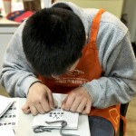 小羊苗朋友將臉湊近提袋上，仔細(xì)將貼紙慢慢地貼上，盡可能確保貼紙有貼正不歪斜。從肢體動(dòng)作，可以曉得小羊們做每件事比別人費(fèi)力，但不減心意。