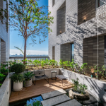 四季合院，每三層設(shè)計(jì)一處公共大露臺(tái)，從梯廳走入彷彿大家庭的合院(埕)，提供住戶們休憩及交誼空間，搭配四季主題的呼應(yīng)，此為七樓的夏季-種植小花紫薇與厚葉石斑木。