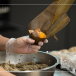 將粽葉三分之一處折起，交叉形成漏斗狀，轉(zhuǎn)著處末端折一個折角，再將內(nèi)餡包入。