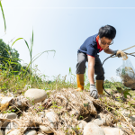 從石縫中抽出韌性的橡膠圈，岸邊的垃圾也不可輕忽，可能會因?yàn)闈q潮後的潮水而沖刷到溪裡。