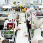 新業(yè)同仁與甘霖志工們分工合作，以生產(chǎn)線的方式有序地進(jìn)行，將熱騰騰的餐食迅速裝盒，確保長輩能準(zhǔn)時享用午餐。